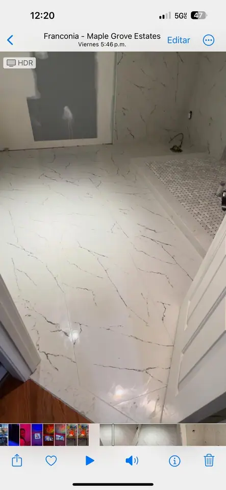 Walk-in shower with marble walls, mosaic floor, and a tiled corner bench