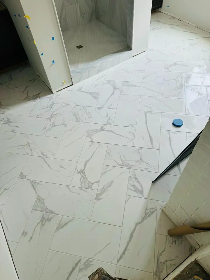 Bathroom floor tiled in a marble-look herringbone pattern