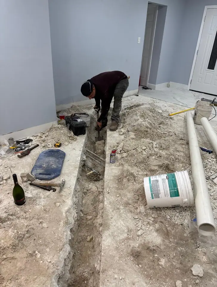 Worker cutting a trench in a concrete slab to set plumbing lines