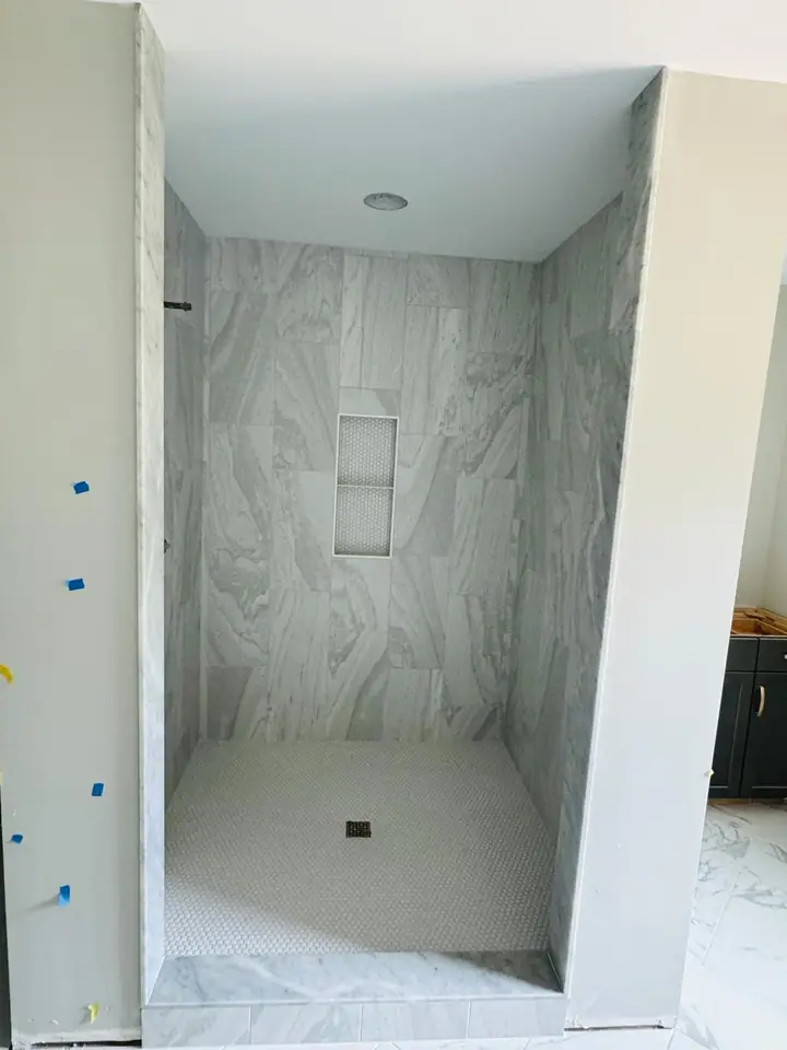 Walk-in shower with a hexagonal mosaic niche and matching floor
